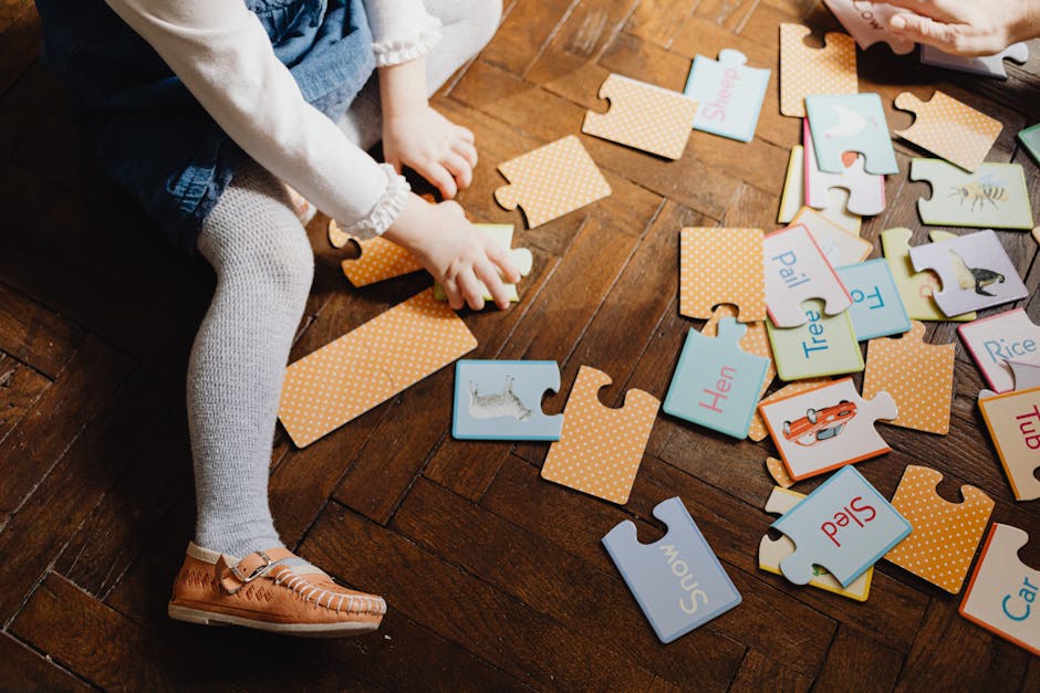 Child engaging with educational puzzle pieces on wooden floor indoors, fostering learning and play.