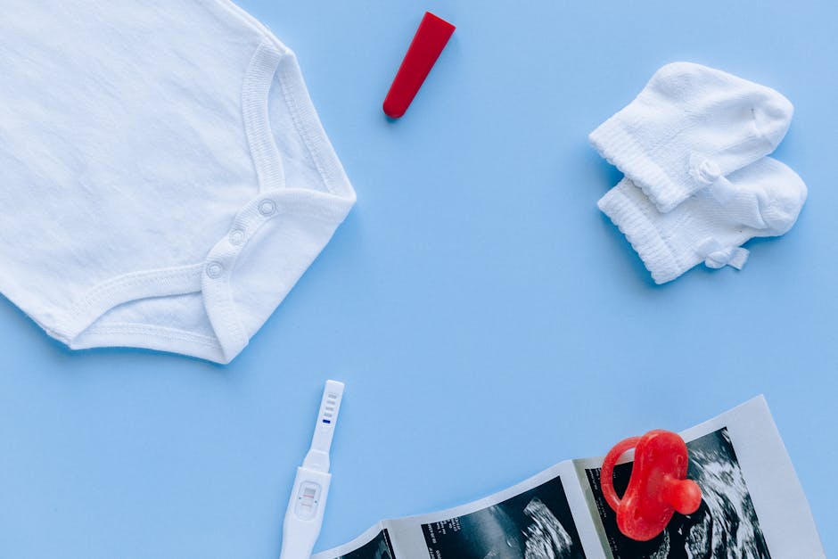 Flat lay of baby essentials and a pregnancy test on a blue background.