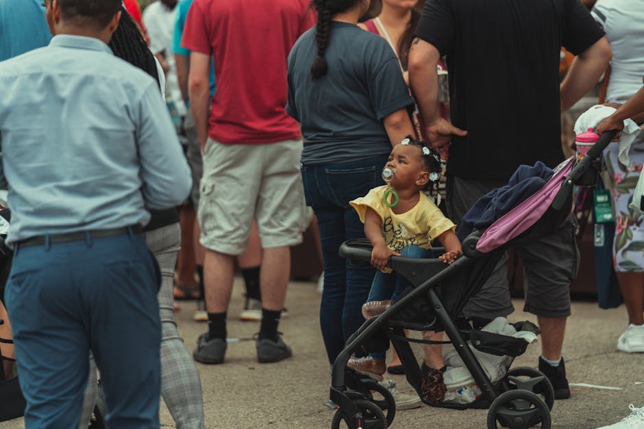 A diverse crowd in a vibrant urban setting featuring a child in a stroller.