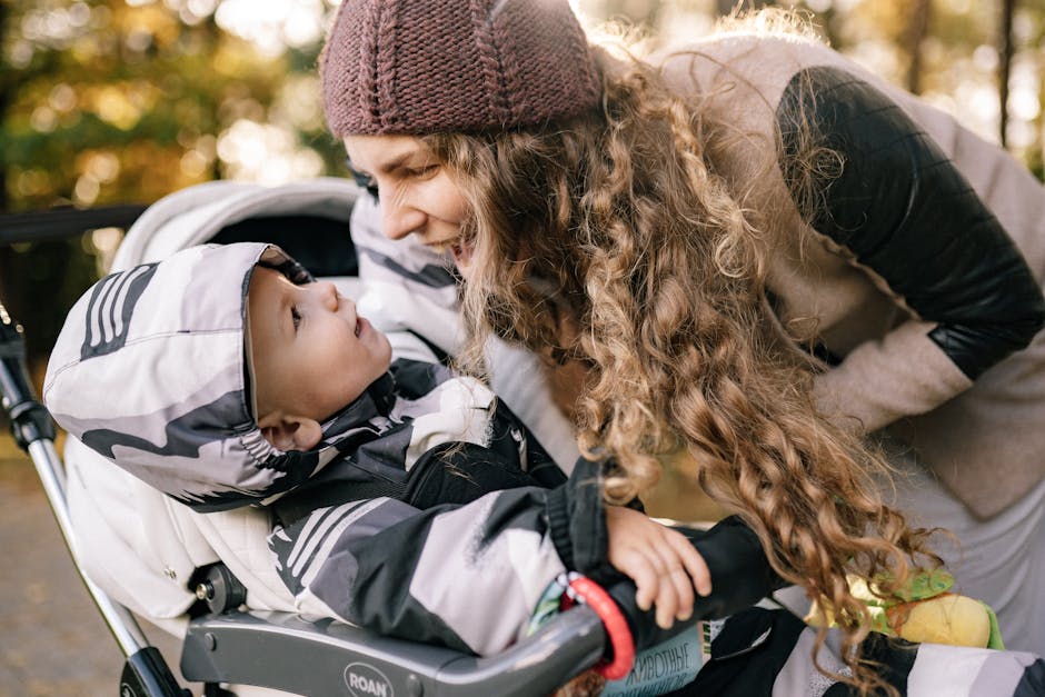 A joyful mother engaging with her baby in a stroller during a sunny day stroll.