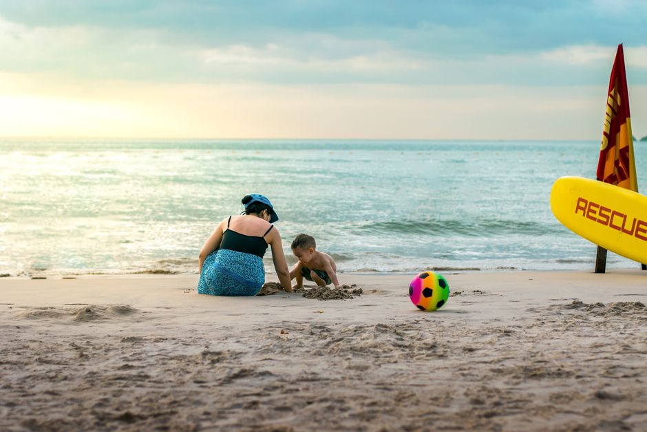 A joyful beach scene of a mother and child playing near the ocean at sunset.