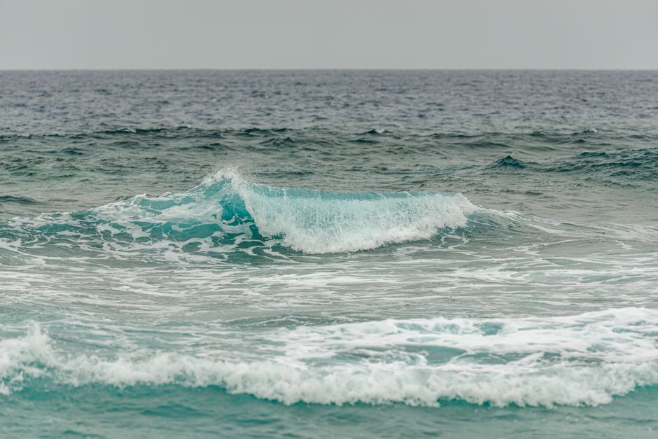 A calming ocean wave breaking on the sea surface under a cloudy sky, capturing the tranquility of nature.