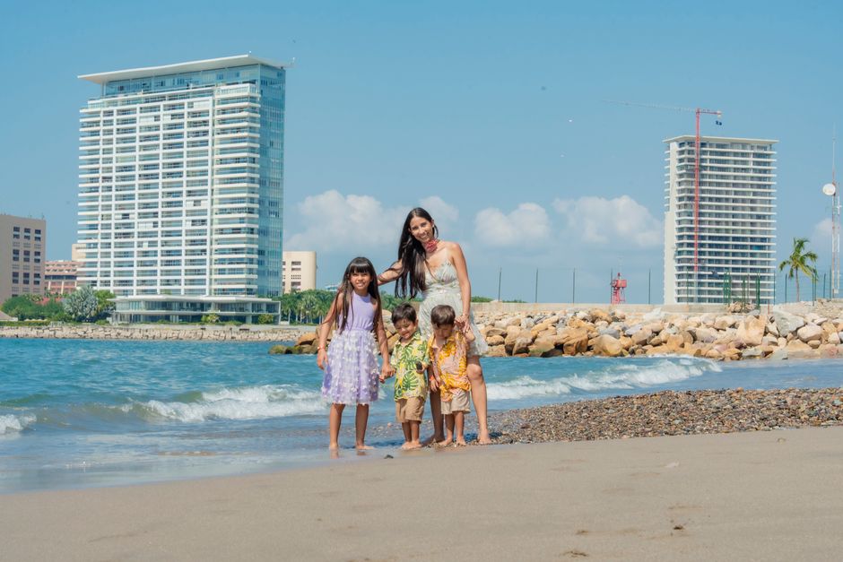 A family having fun on a sunny beach day with skyscrapers in the background.