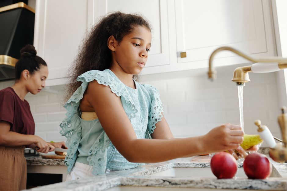 Girl helping to wash up at the kitchen sink