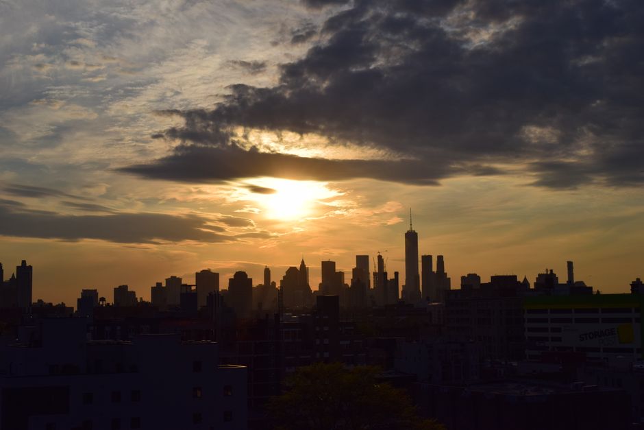 Silhouette of the New York City skyline against a vibrant sunset sky.