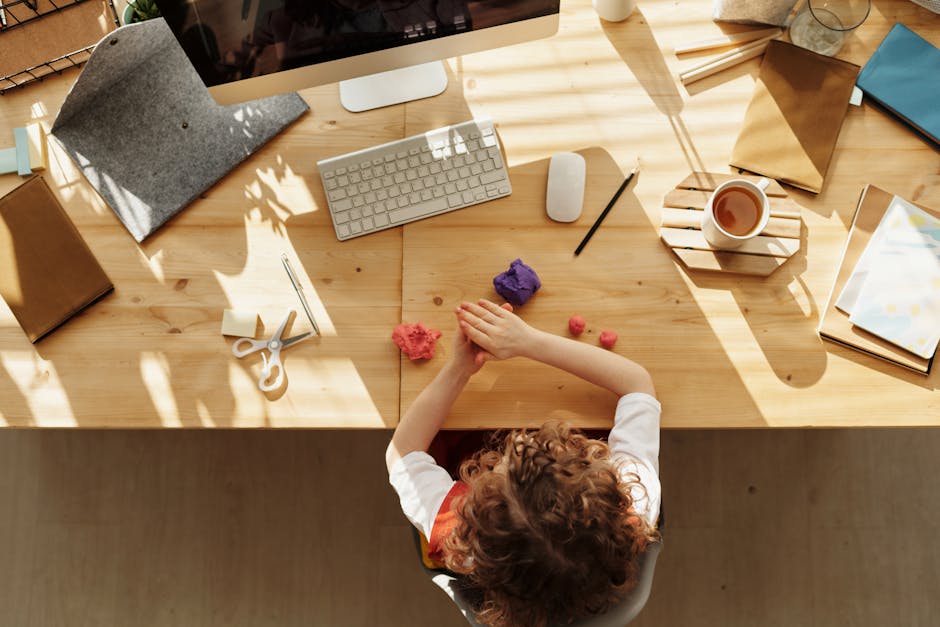 A child engaged in crafting activities at a home desk, surrounded by stationery and computer.