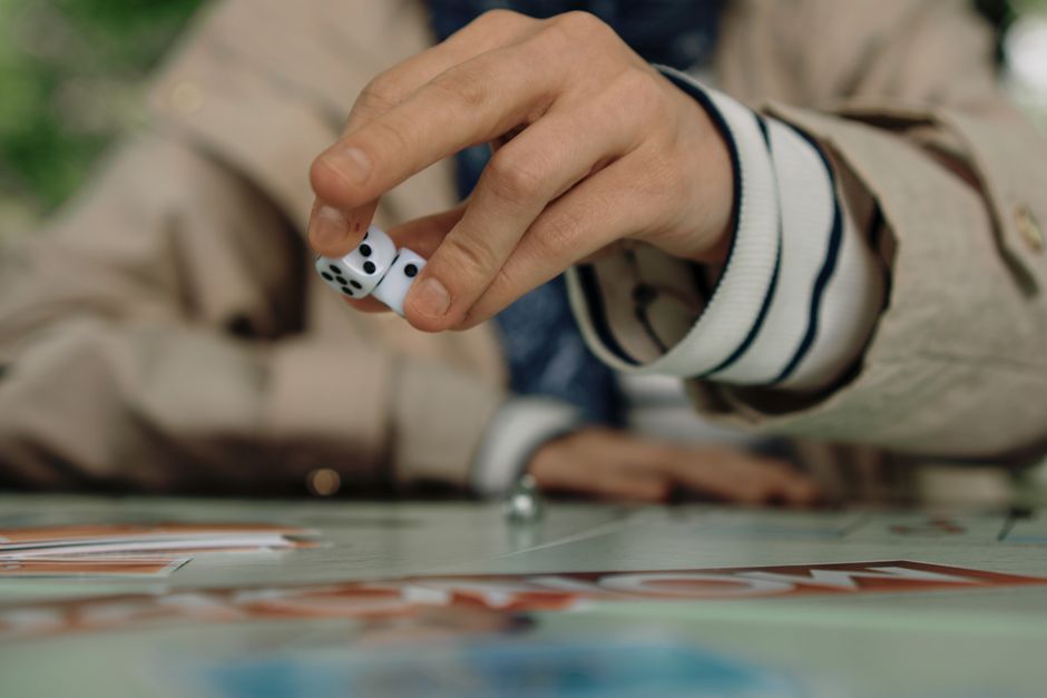 Person rolling dice during a board game, focusing on the hand and dice mid-action.