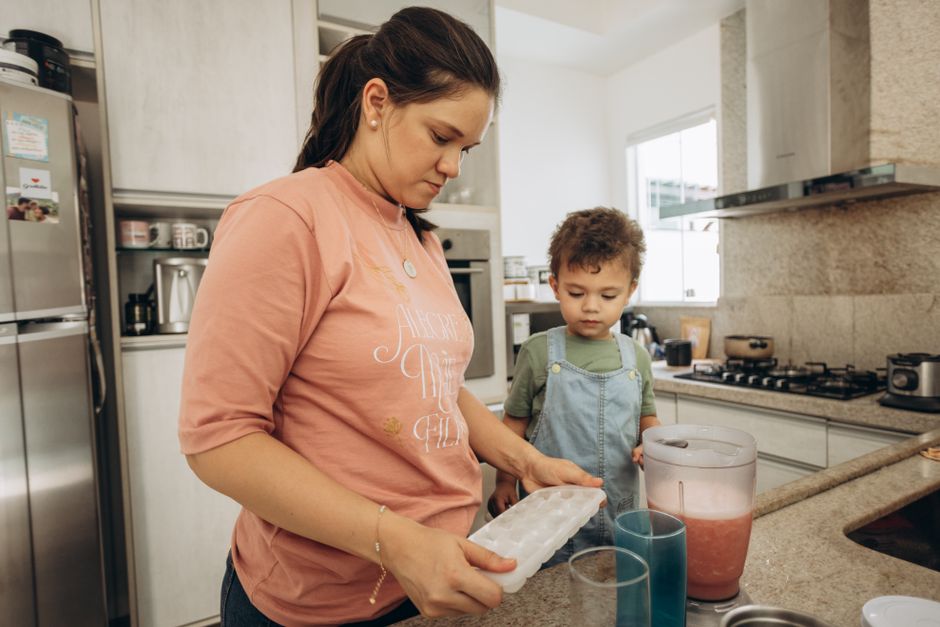 A woman and her son making a drink together in a modern kitchen.