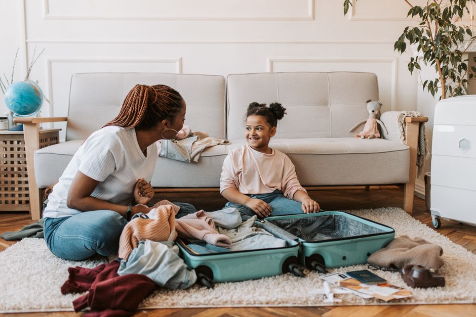Mother and daughter packing a suitcase together at home, enjoying family time.