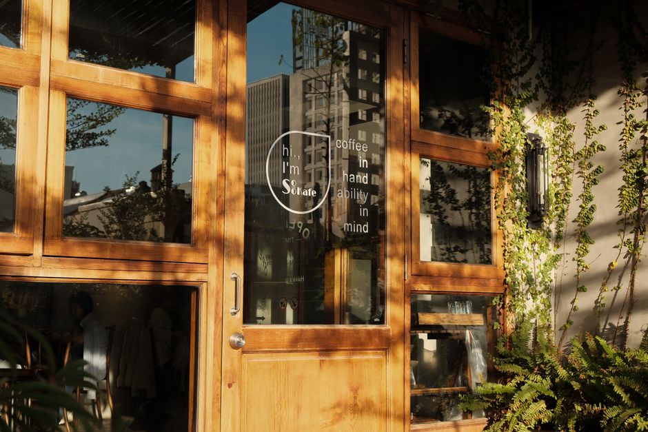 Warm sunlight on a café entrance with wooden doors and greenery.