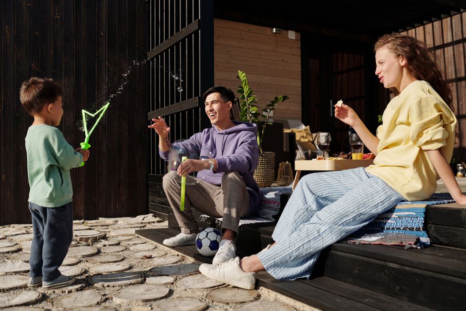 A family spends quality time playing with bubbles outside on a sunny day.