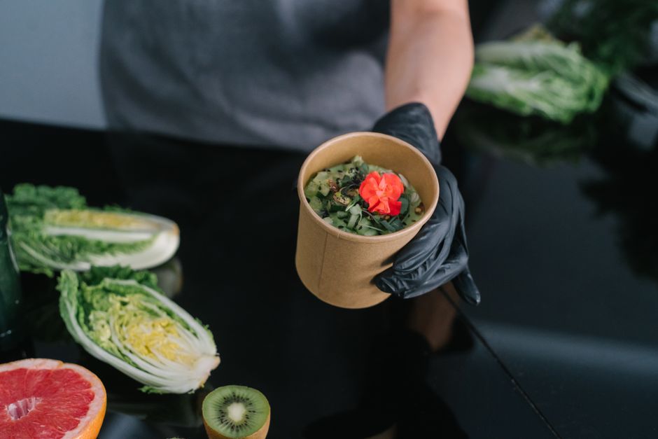 A hand holding a salad bowl with fresh vegetables and a colorful garnish, emphasizing healthy eating.