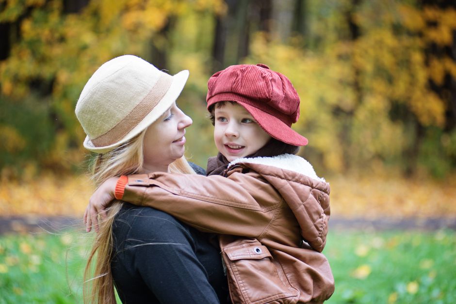 A joyful mother and child enjoying a sunny day in an autumn park.