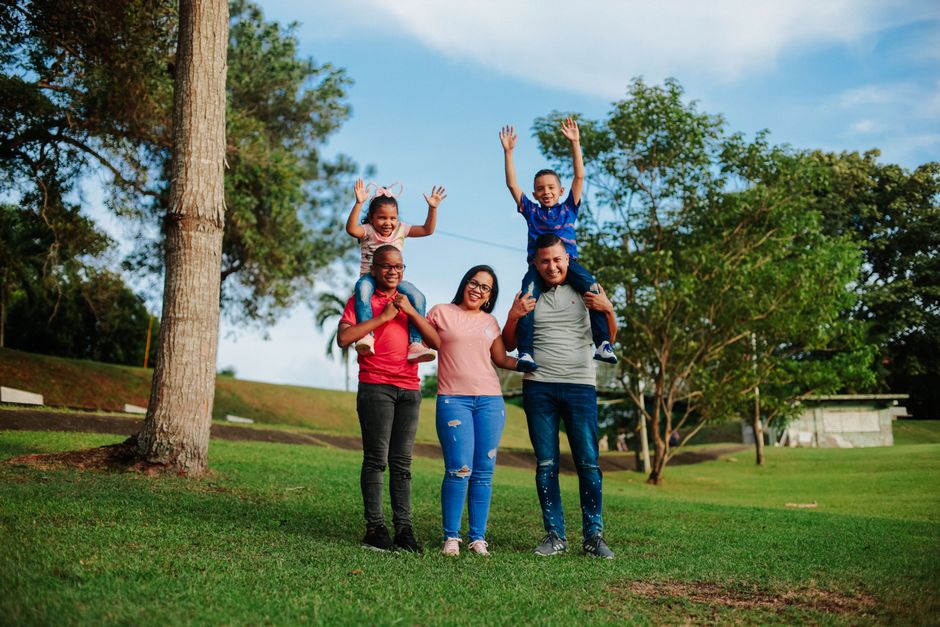 Smiling family of four having fun outdoors together at the park on a sunny day.