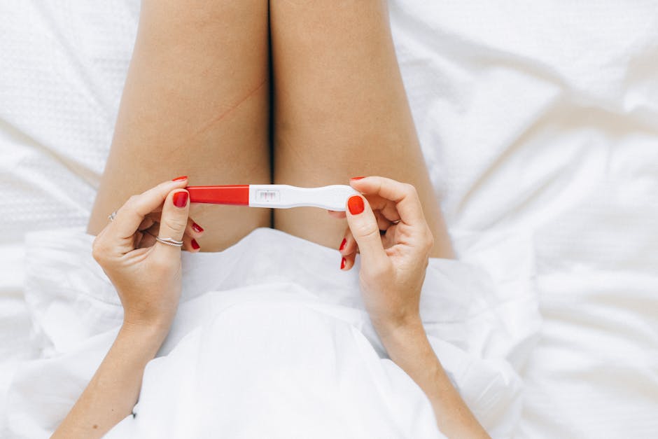 A close-up of a woman's hands holding a positive pregnancy test with two lines.