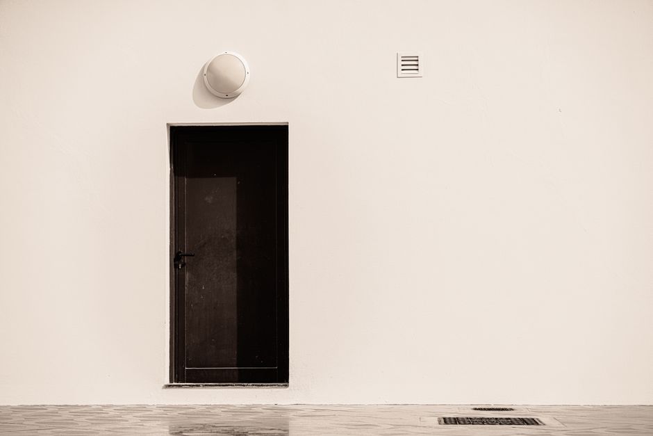 A minimalist view of a dark door on a light wall in Dubai, showcasing modern architecture.