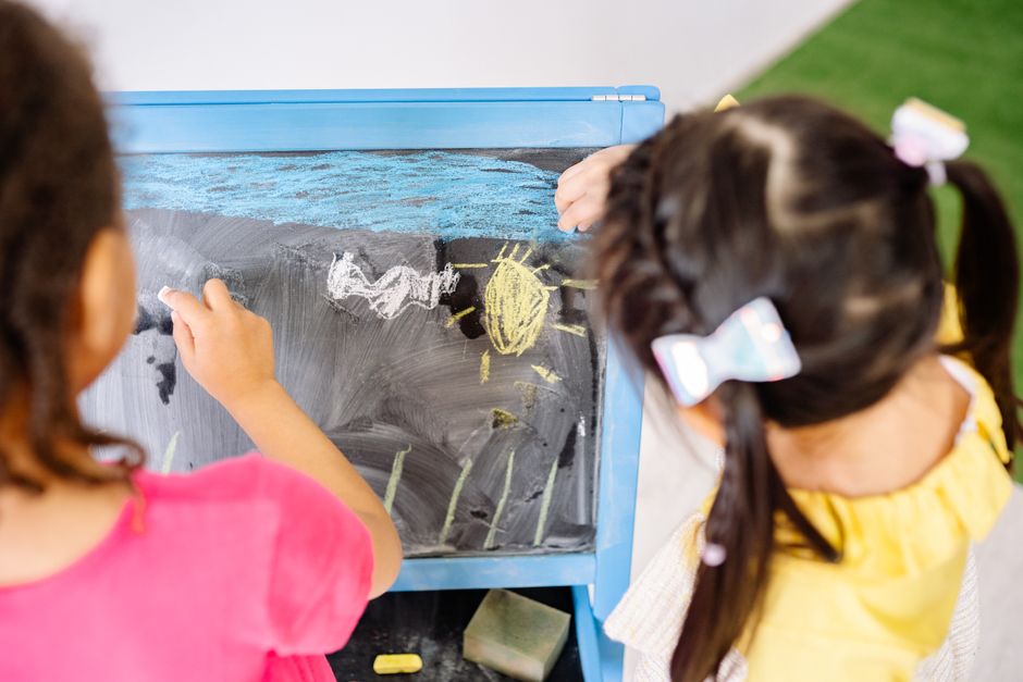 Children enjoying drawing on a blackboard in a vibrant classroom setting, highlighting creativity and education.