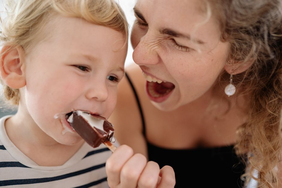 A playful moment captured between a mother and her son enjoying a chocolate ice cream.