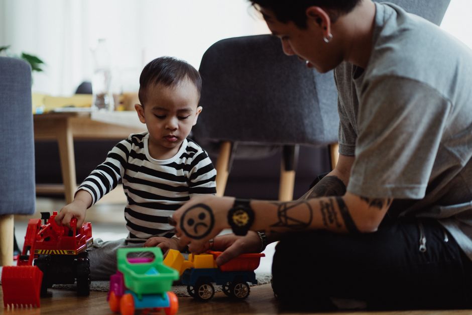 Father and child enjoy quality time playing with colorful toy cars at home.