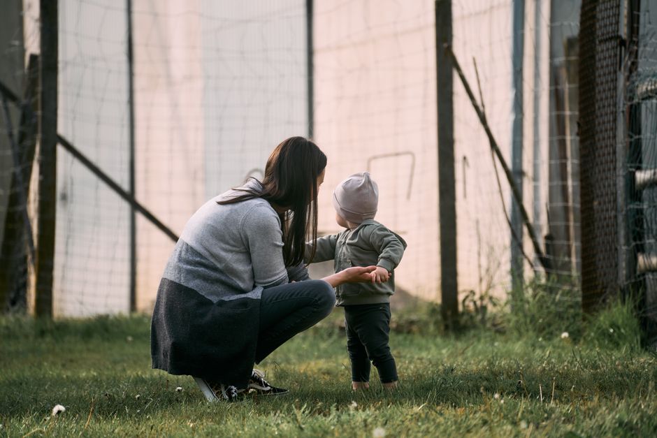 A mother crouches bonding with her toddler outdoors in Graz, Austria.