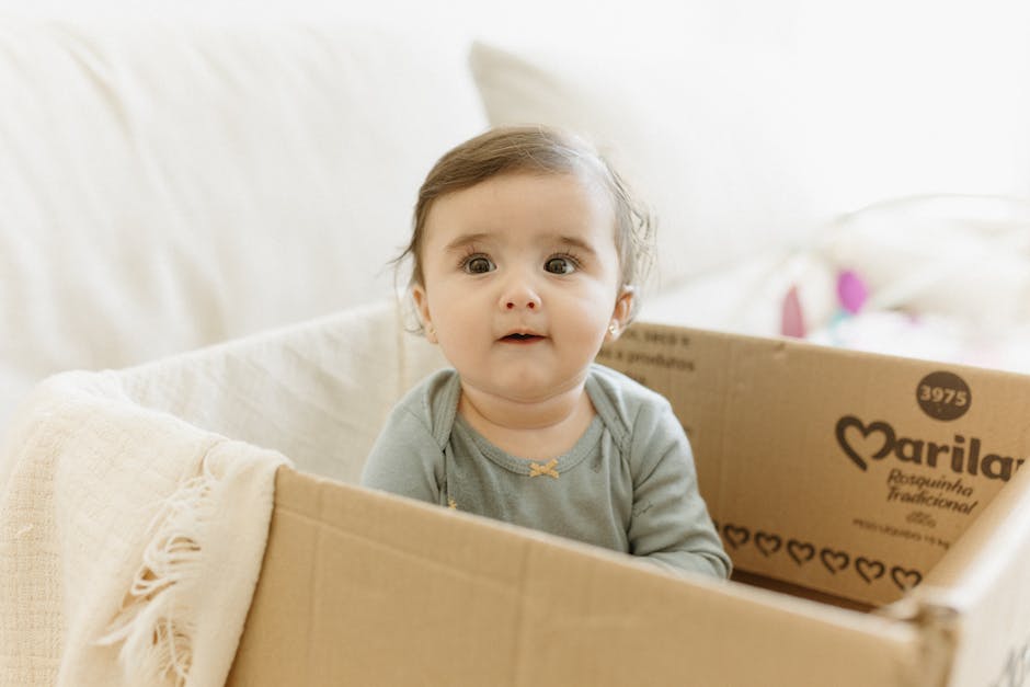 Cute baby sitting in a cardboard box in a cozy bedroom setting, perfect for family moments.